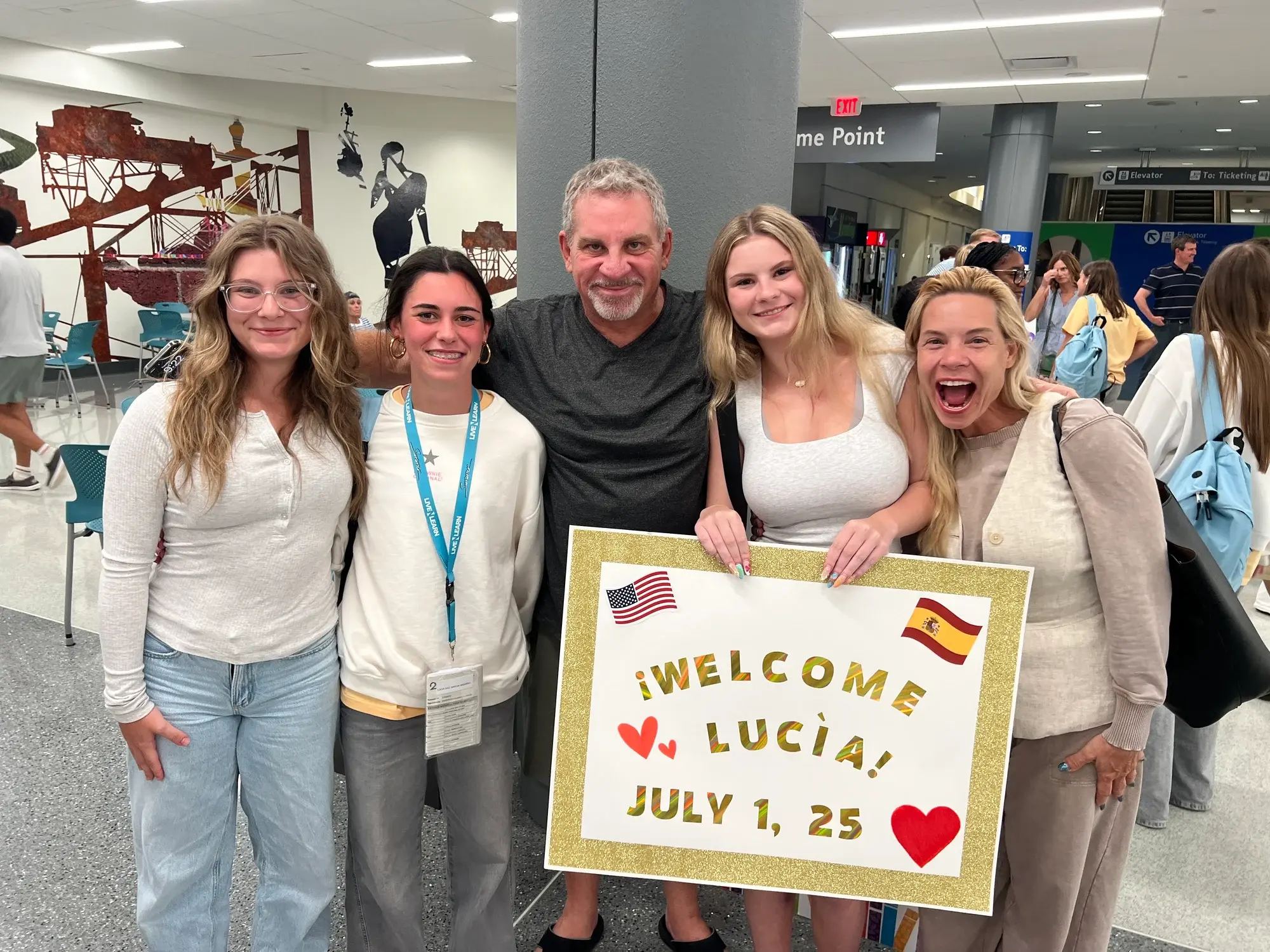 A host family holding a Welcome Lucia sign at the airport